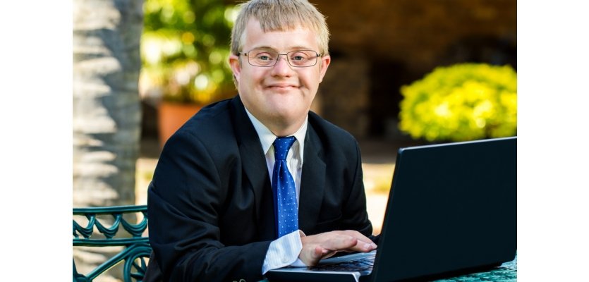 handicapped businessman working with laptop Close up portrait of young businessman with down syndrome doing accounting on laptop outdoors. elearning brothers